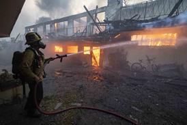 A LAFD firefighter hoses down an apartment building in Altadena, California